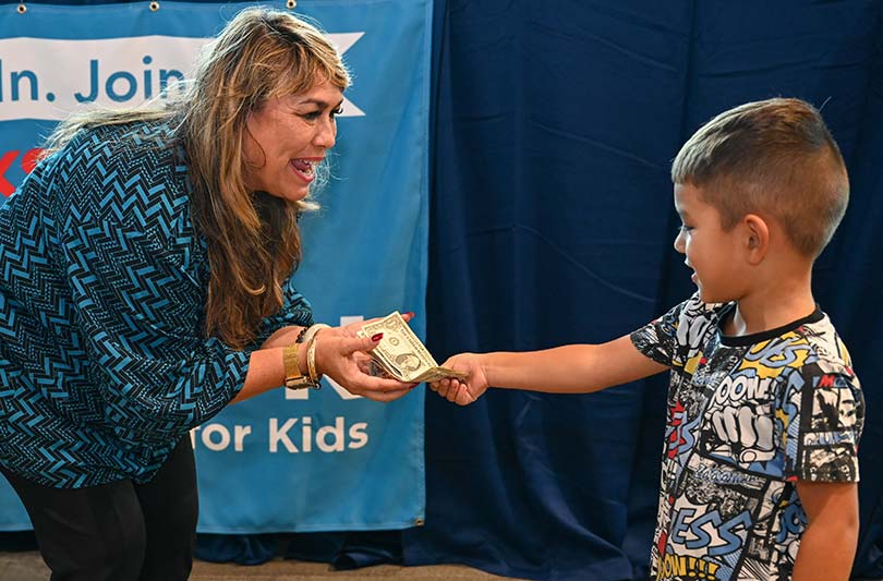 Child donating cash to adult woman