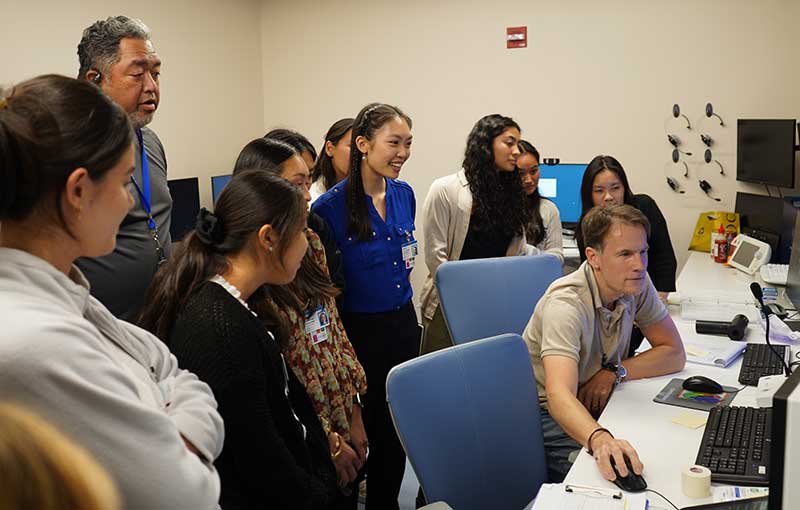 Group of interns gathered around man at a computer