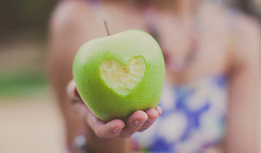 Green apple with a heart-shaped bite out of it.