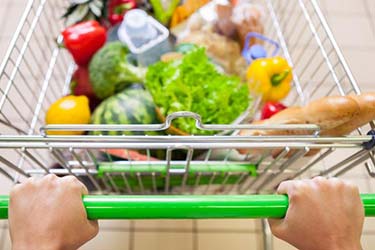 A man pushes a grocery cart full of fresh fruits and vegetables