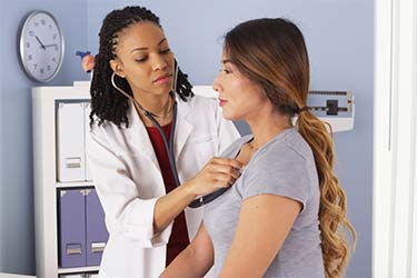 Patient with her doctor holding stethoscope to heart.