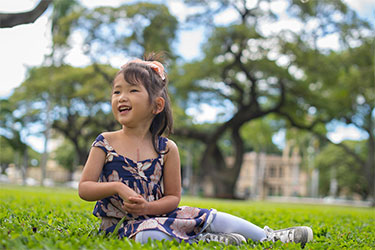 Young girl sitting on lawn smiling.
