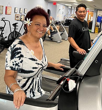 Smiling woman on a treadmill with a man on another treadmill.
