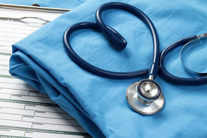 Stethoscope in heart shape on top of blue scrubs.