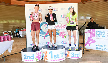 Three female runners on the awards podium.