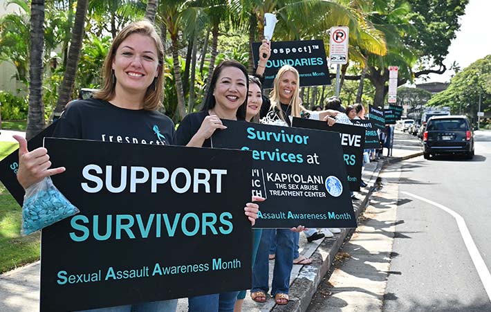 People wearing denim and waving signs in support of Sexual Assault Awareness Month.