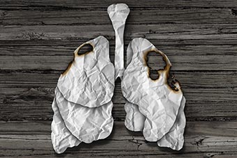 Illustration of lungs cut out of paper with burn holes in them.