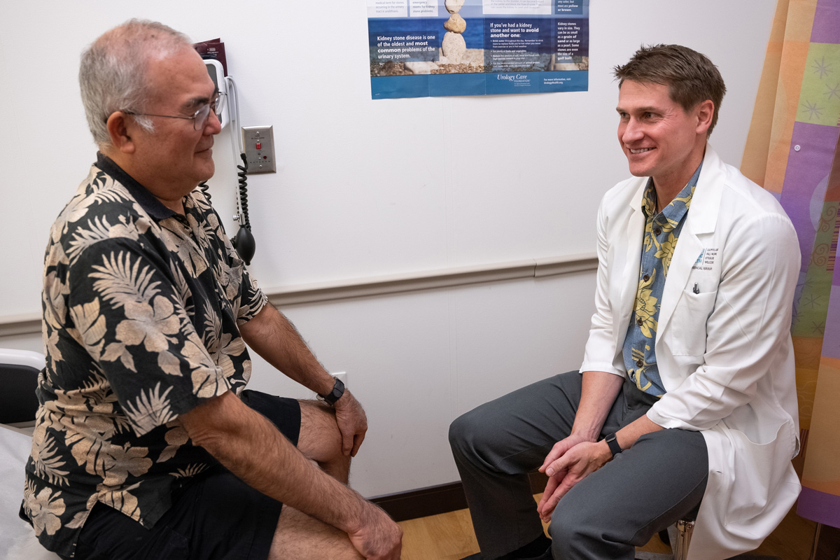 A male doctor and male patient sit in an exam room