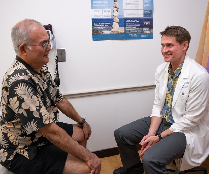 A male doctor and male patient sit in an exam room