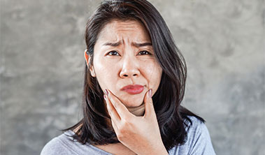 Women holding her chin and making a concerned face.