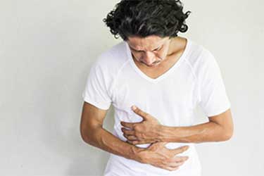 Man holding stomach and looking down