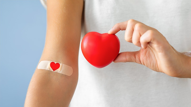 arm of blood donor with a heart printed bandage holding a heart