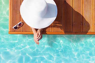 Overhead view of woman poolside wearing a large white hat.