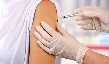 Close up of shoulder being injected with a vaccine by gloved provider.