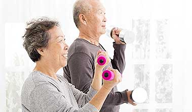 Senior man and women working out with light hand weights.