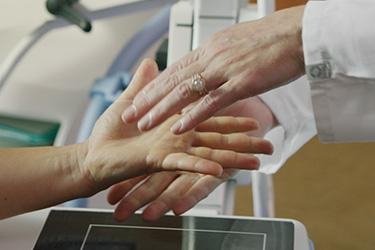 Hands of a physician above and below hands of a patient being examined.