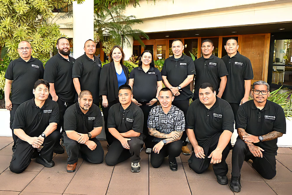 Large group with two rows of facilities staff in black polo shirts at Pali Momi Medical Center.