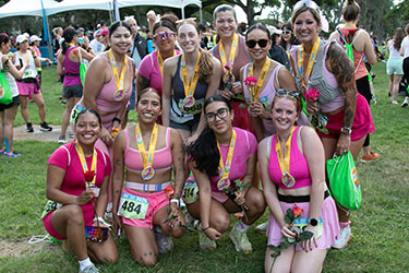 Group shot of women runners wearing medals after a race.
