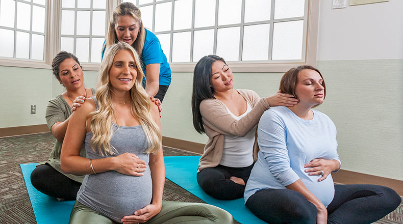Pregnant women and their partners sitting together as a nurse educator provides guidance in a maternity class.
