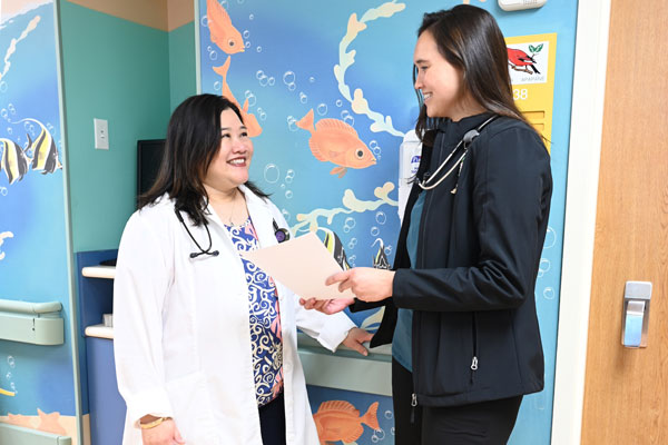 Dr. Natascha Ching (left) and pediatric resident Dr. Brachelle Nueku discuss education about vaccines for the pediatric residency program.