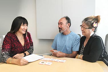 Three people sitting at a table with papers in front of them.