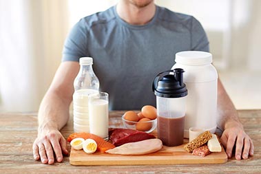 Man at table with dairy, milk, meat and protein drink in front of him.
