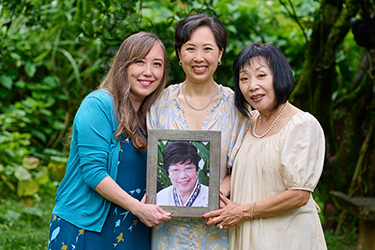 Three sisters holding a portrait of their mother.
