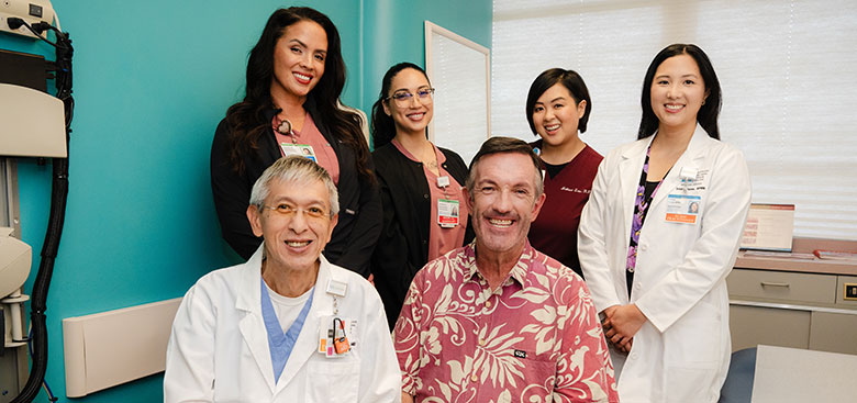 Group short of male patient with care team in a medical office.