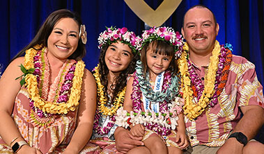 Beautiful family with two young girls all draped in lei.