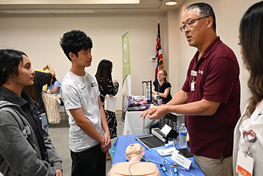 Physician speaking with high school students about cardiology and showing specialized medical instruments.