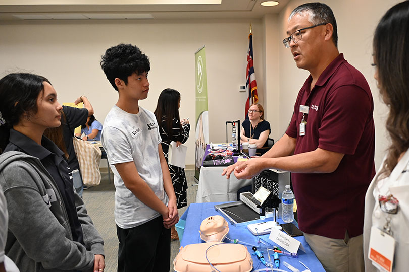 Physician speaking with high school students about cardiology and showing specialized medical instruments.