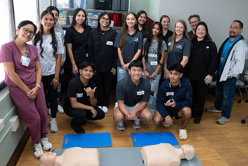 Group shot of smiling students, instructors and health care providers with simulation dummies.