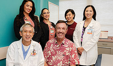 Patient and staff group shot in medical examination room.