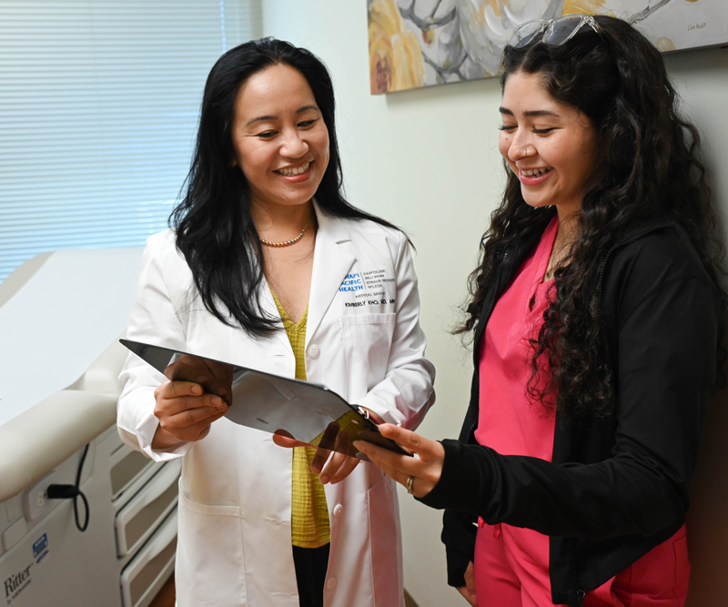 a doctor and medical assistant look over a patient's chart in an exam room