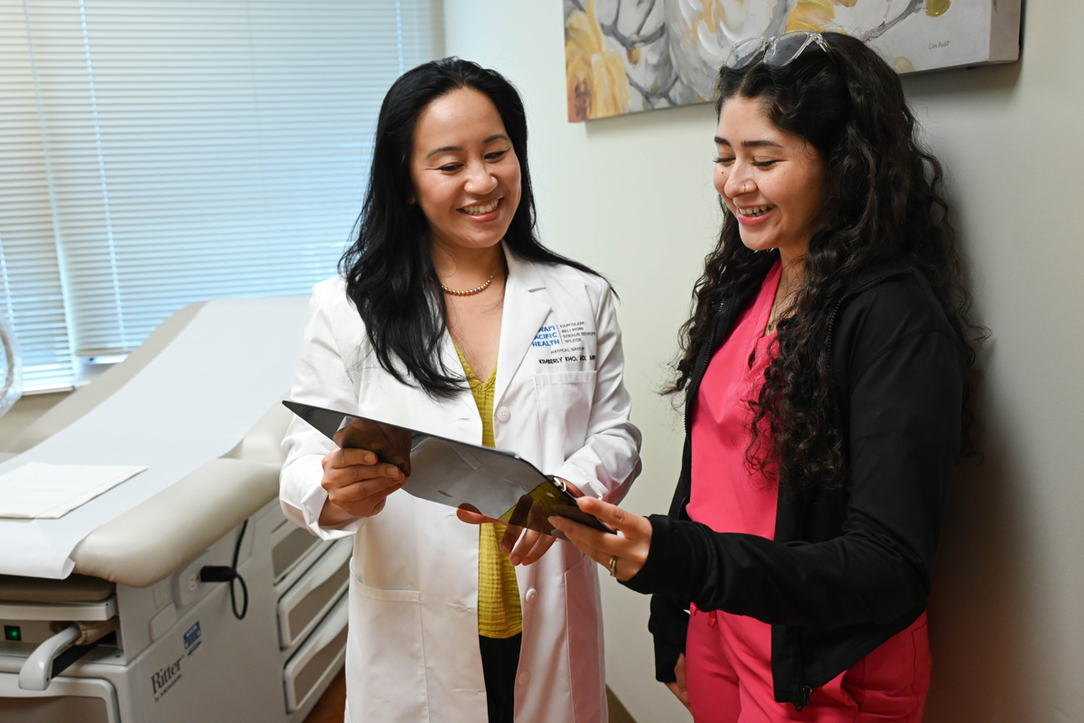 a doctor and medical assistant look over a patient's chart in an exam room
