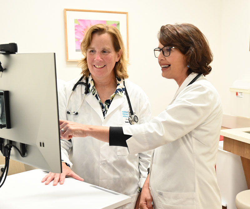 a female doctor and female physician assistant look at a computer in a clinic room at the Straub Benioff Mililani Clinic