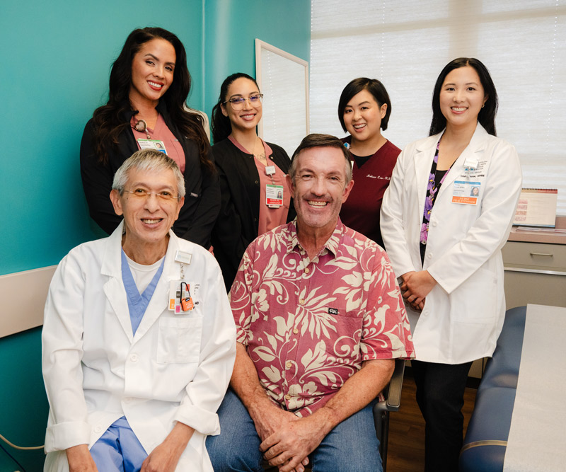 Patient and staff group shot in medical examination room.