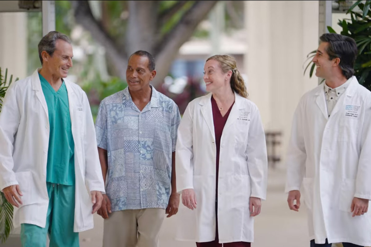 three physicians walk with a patient in the spine at Wilcox Medical Center