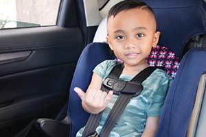 Young boy smiling and giving shaka while sitting in his car seat.