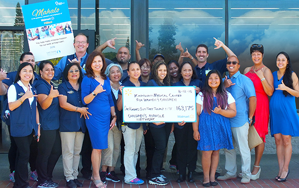 group from Kapiolani posing for a group photo with a donation check from Walmart and Sam's Club