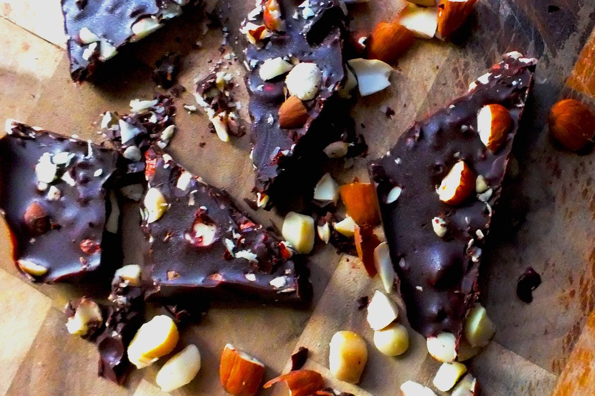 Pieces of nut-filled chocolate with nut pieces scattered around.