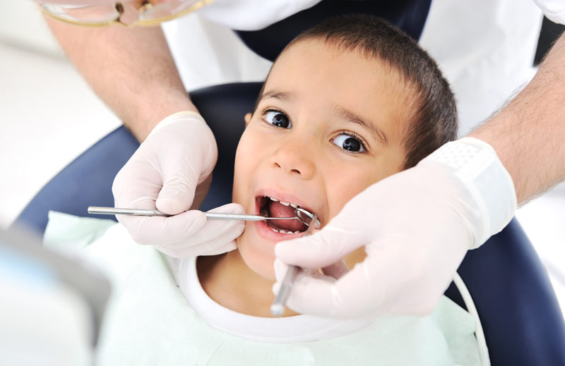 a young child with dental tools in the mouth