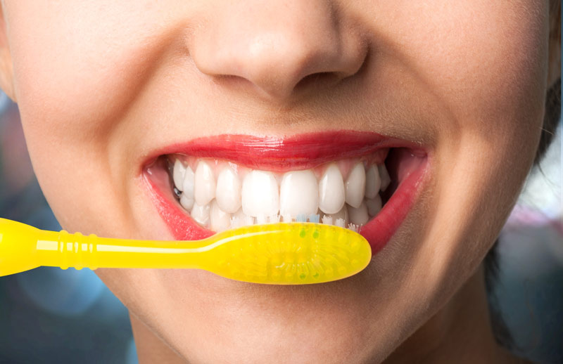 close up of a lady smiling and brushing her teeth