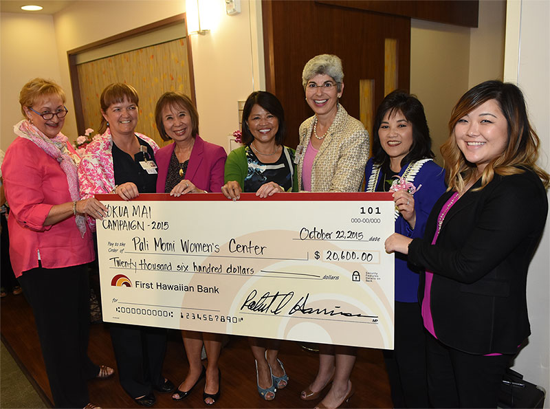 group photo from a pali momi women's center holding up a large donation check