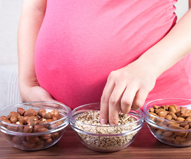 Pregnant woman eating various nuts