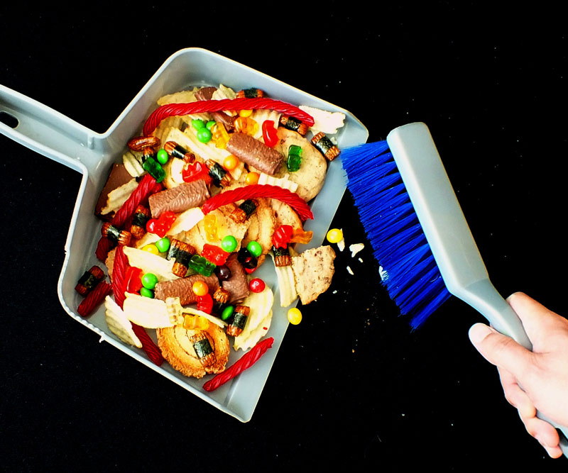 Person sweeping unhealthy candies, cookies and sweets into a dustpan