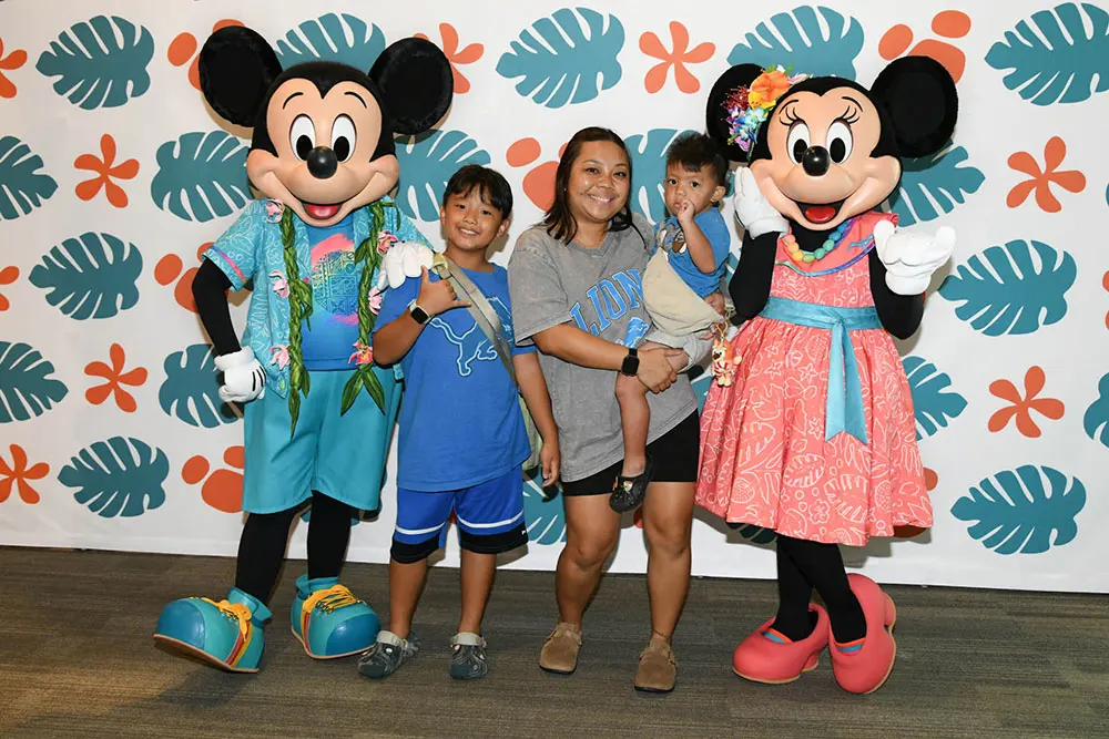 Young boys with their mother alongside Mickey and Minnie characters actors.