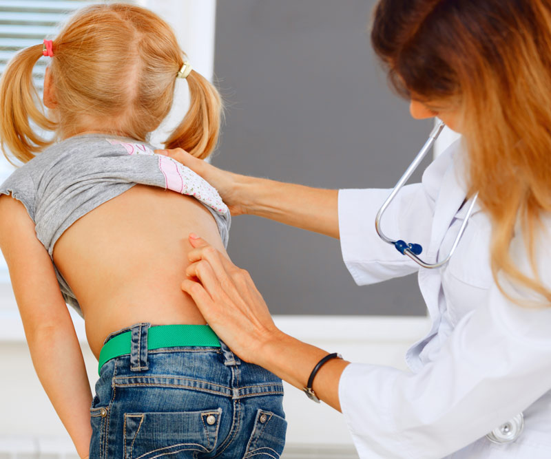 child getting her spine examined by doctor