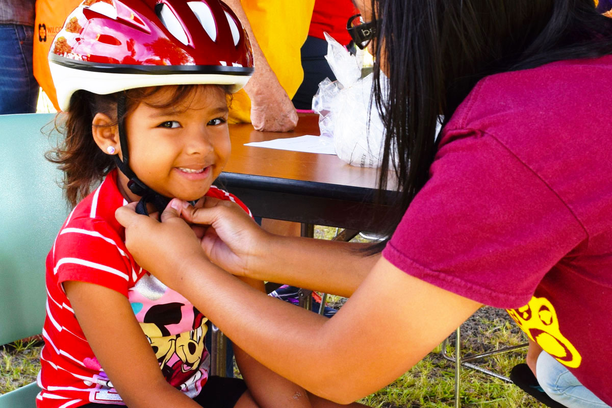 a mother tying bicycle helmet to her child