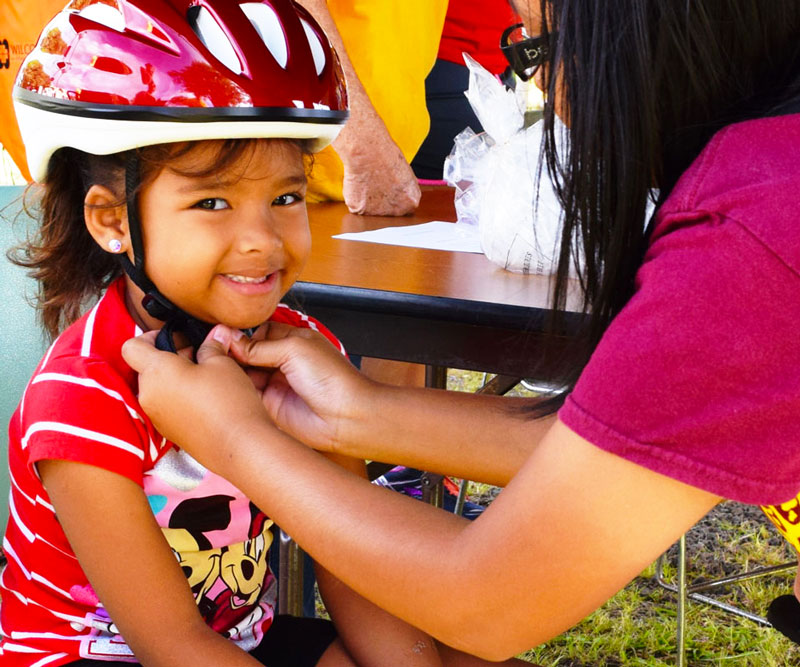 a mother tying bicycle helmet to her child